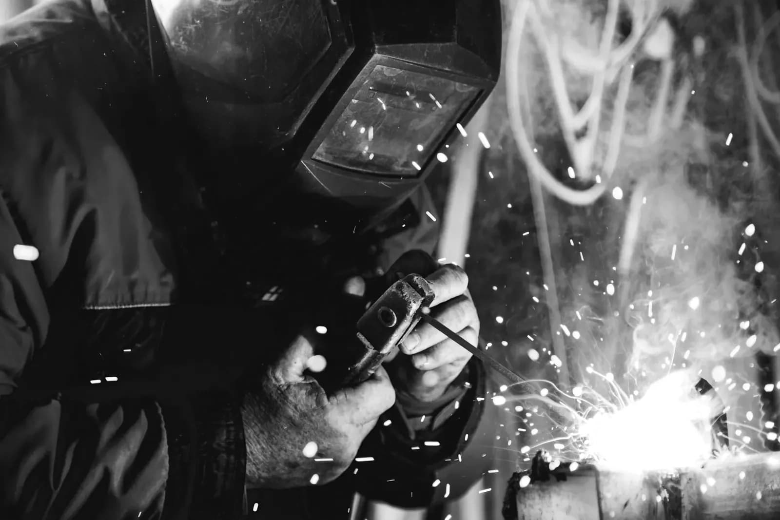 Welder inspecting a joint with sparks flying